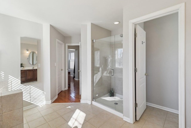 bathroom with a stall shower, tile patterned flooring, vanity, and baseboards