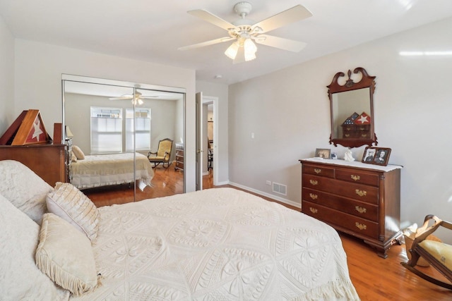 bedroom featuring baseboards, visible vents, a ceiling fan, wood finished floors, and a closet