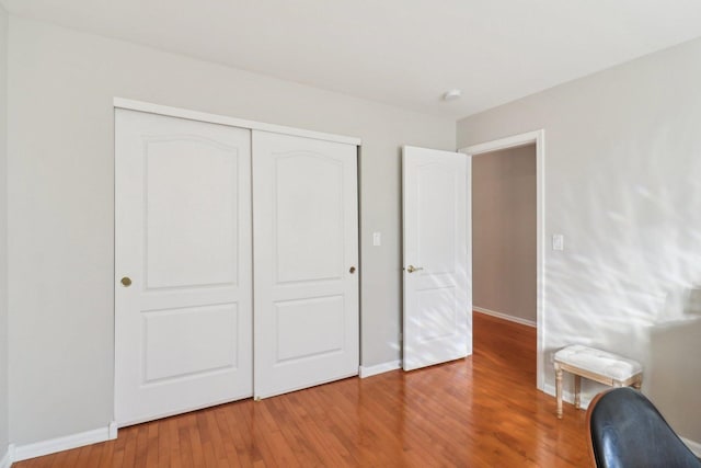 bedroom with a closet, baseboards, and wood finished floors