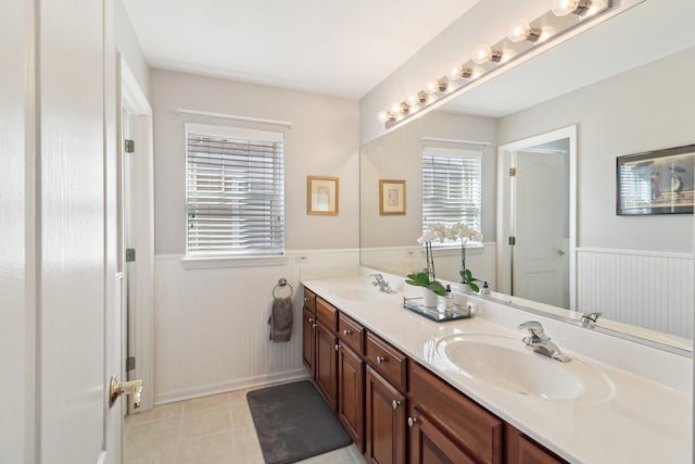 full bathroom with double vanity, wainscoting, a sink, and tile patterned flooring