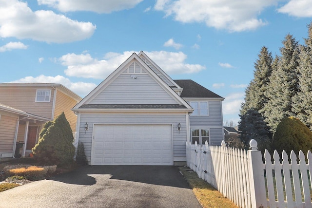 view of front of home with a garage, driveway, and fence