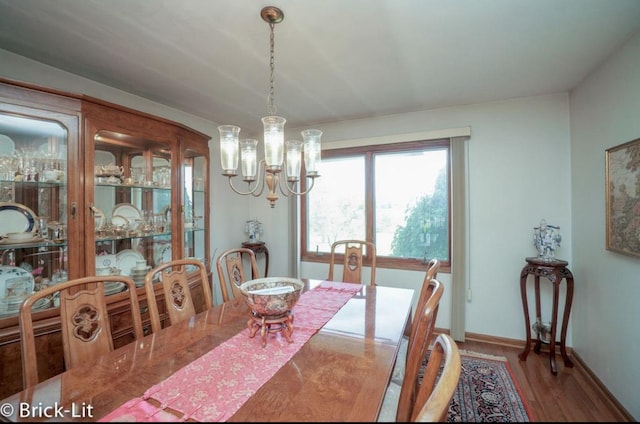 dining space featuring baseboards, wood finished floors, and an inviting chandelier