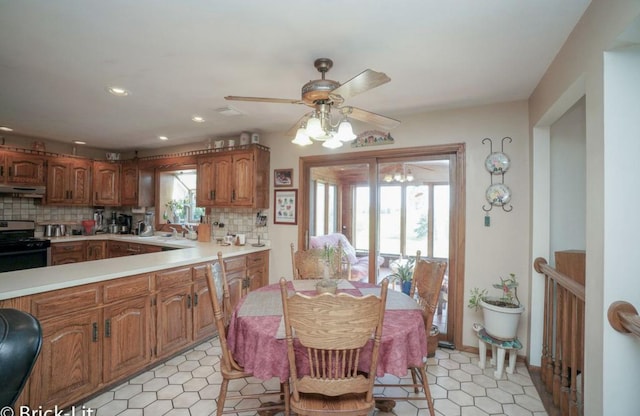 kitchen with under cabinet range hood, stainless steel gas range oven, light countertops, and backsplash