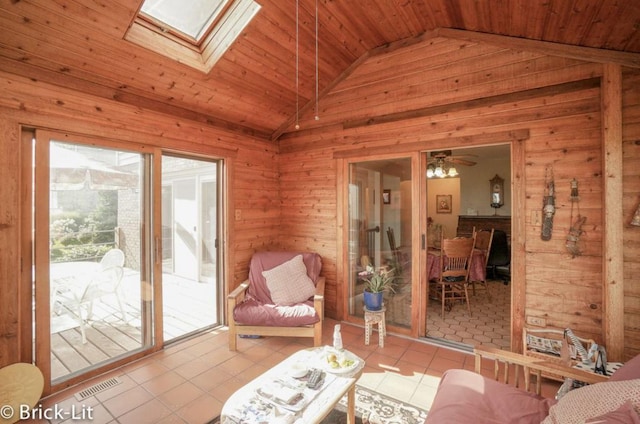 interior space with wooden ceiling, vaulted ceiling with skylight, visible vents, and wood walls