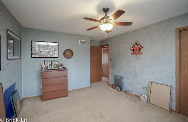 carpeted spare room with baseboards, a fireplace, visible vents, and a ceiling fan