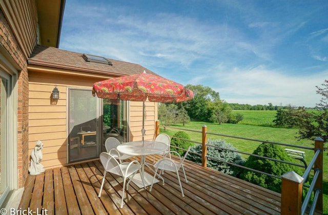 wooden terrace with outdoor dining space and a rural view