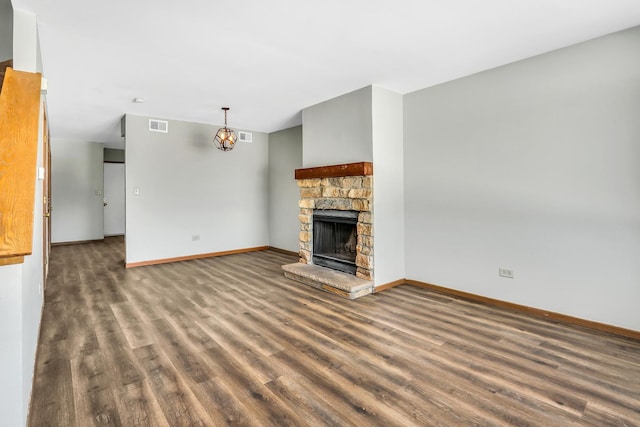 unfurnished living room featuring baseboards, visible vents, dark wood finished floors, and a fireplace