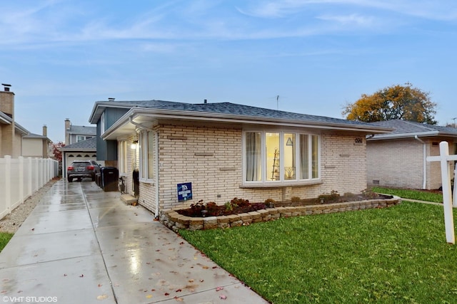 view of front of property featuring brick siding, fence, concrete driveway, roof with shingles, and a front yard