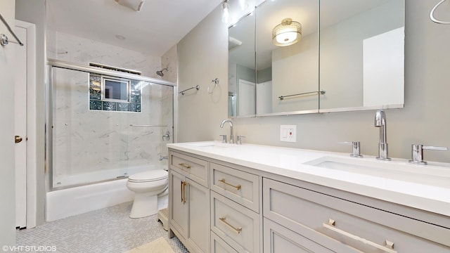 full bath with shower / bath combination with glass door, a sink, toilet, and double vanity