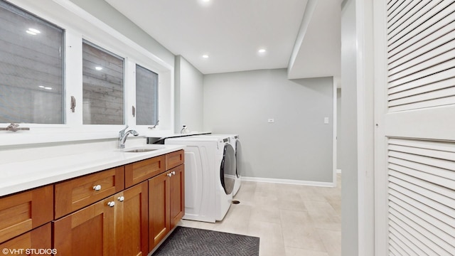 washroom with recessed lighting, cabinet space, a sink, separate washer and dryer, and baseboards