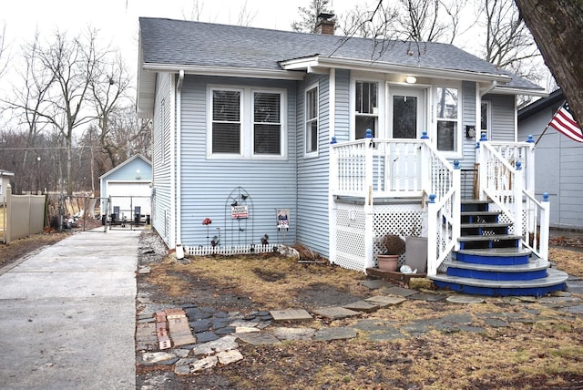 view of front of property featuring an outbuilding, a shingled roof, a chimney, and a garage