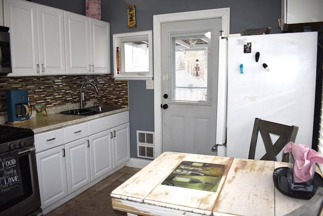 kitchen featuring light countertops, visible vents, decorative backsplash, appliances with stainless steel finishes, and a sink