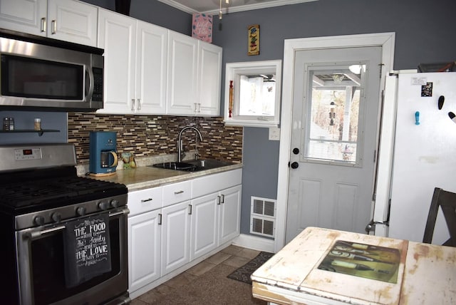 kitchen with a sink, white cabinets, light countertops, appliances with stainless steel finishes, and tasteful backsplash