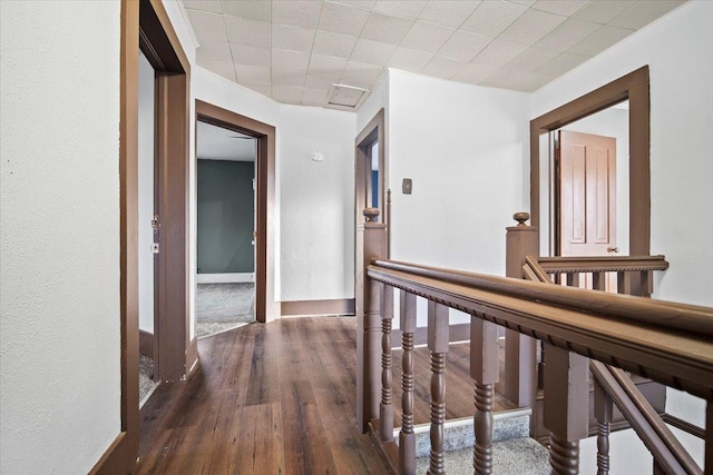 hall featuring baseboards, an upstairs landing, and wood finished floors