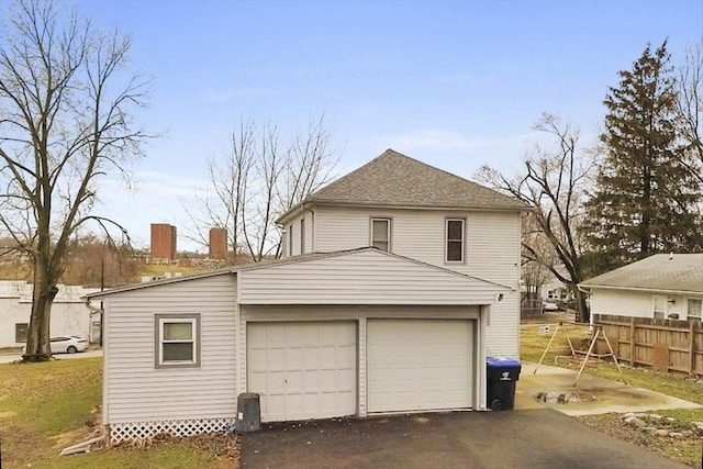 garage featuring driveway and fence