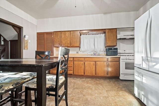 kitchen with white appliances, brown cabinets, and a sink