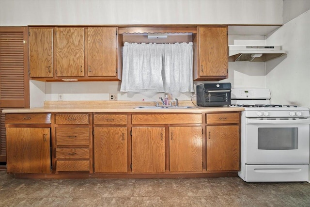 kitchen featuring brown cabinets, white gas range, light countertops, a sink, and under cabinet range hood