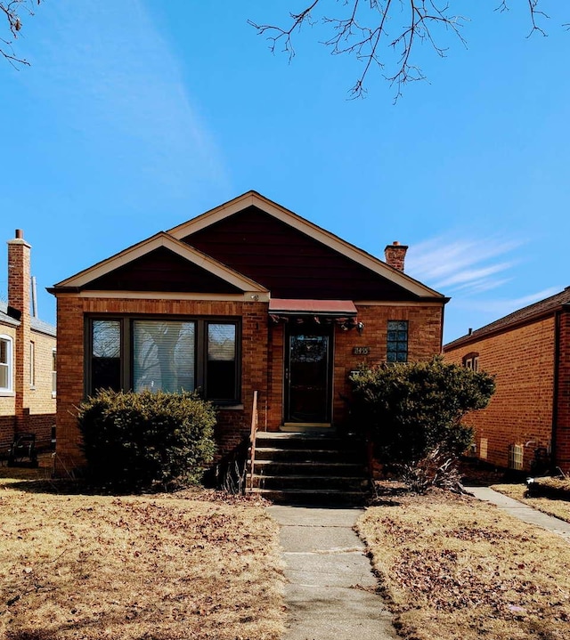 view of front of property featuring a chimney and brick siding