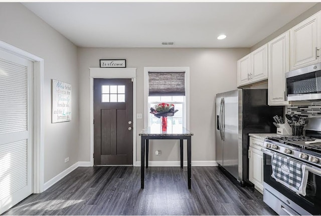 kitchen featuring appliances with stainless steel finishes, decorative backsplash, white cabinetry, and dark hardwood / wood-style floors