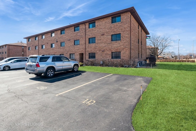 view of building exterior with uncovered parking and central AC unit