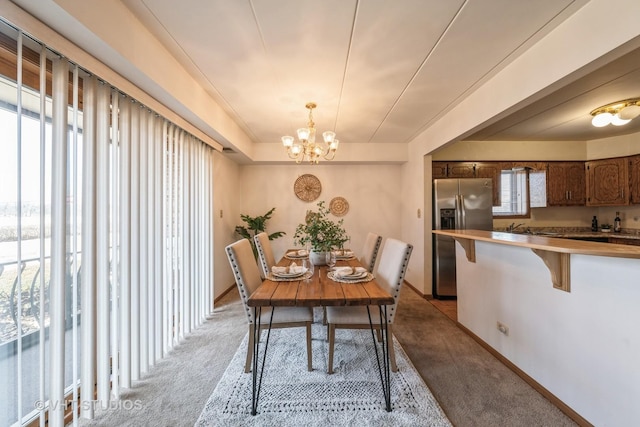 dining space with baseboards, a chandelier, a wealth of natural light, and light colored carpet