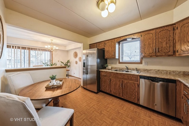 kitchen featuring a wealth of natural light, appliances with stainless steel finishes, brown cabinetry, and a sink