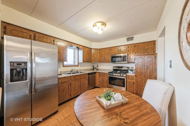 kitchen with brown cabinets, light countertops, visible vents, appliances with stainless steel finishes, and a sink