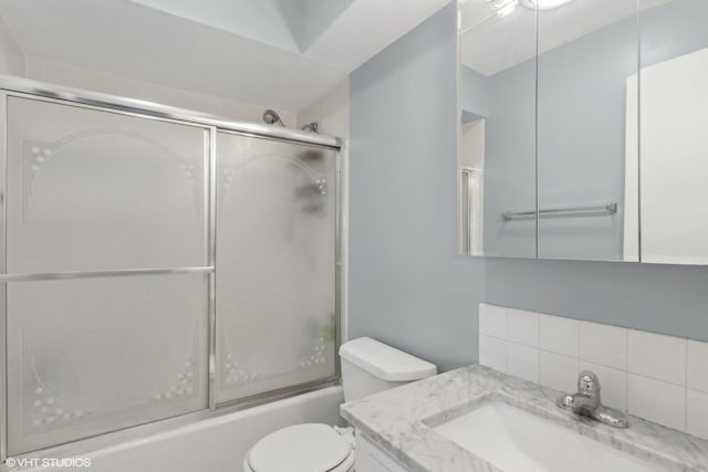 full bathroom with toilet, vanity, backsplash, and enclosed tub / shower combo