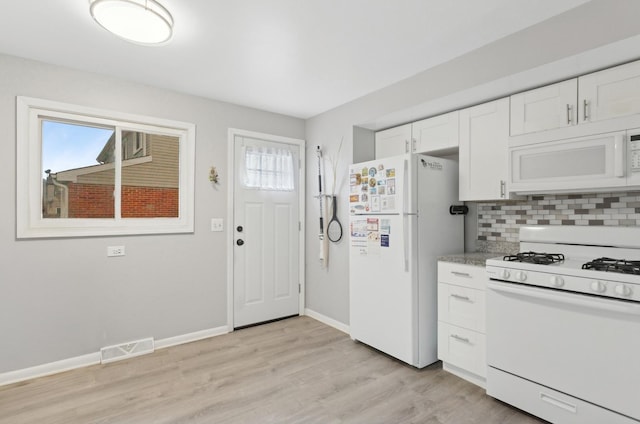 kitchen featuring white appliances, a healthy amount of sunlight, white cabinetry, and decorative backsplash