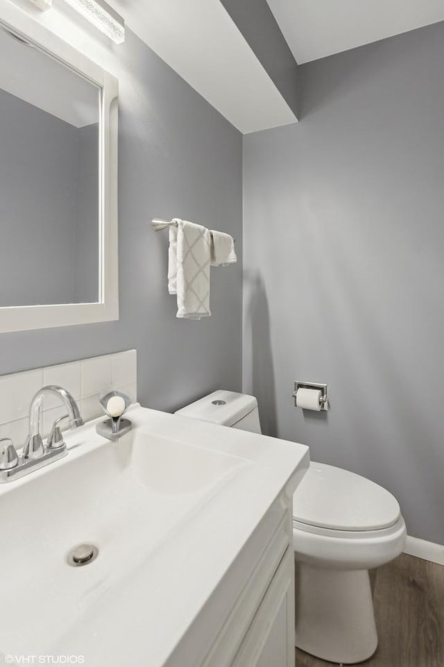 bathroom featuring hardwood / wood-style flooring, vanity, backsplash, and toilet