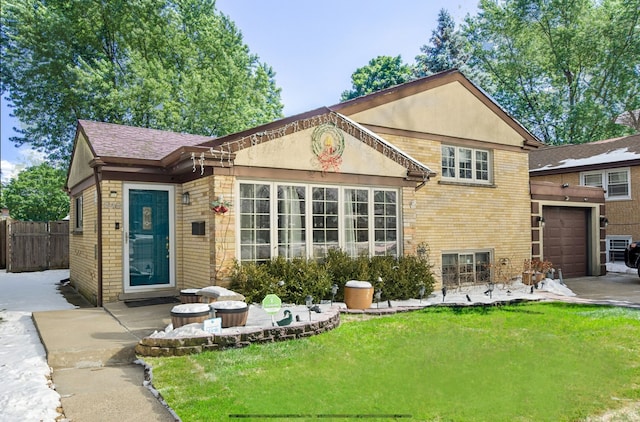 view of front facade featuring a garage, brick siding, a patio, fence, and a front yard