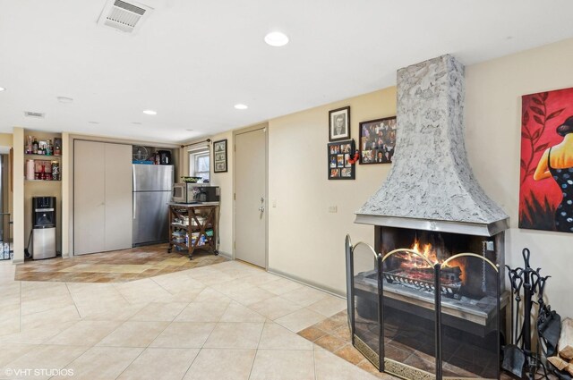 interior space featuring a high end fireplace, visible vents, light tile patterned flooring, and recessed lighting