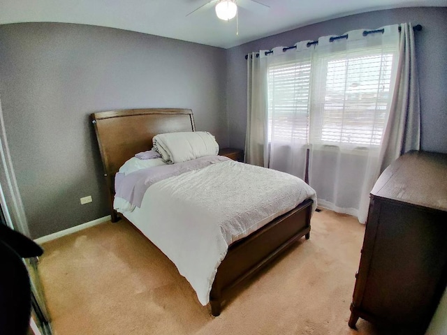 bedroom with a ceiling fan, baseboards, and light carpet