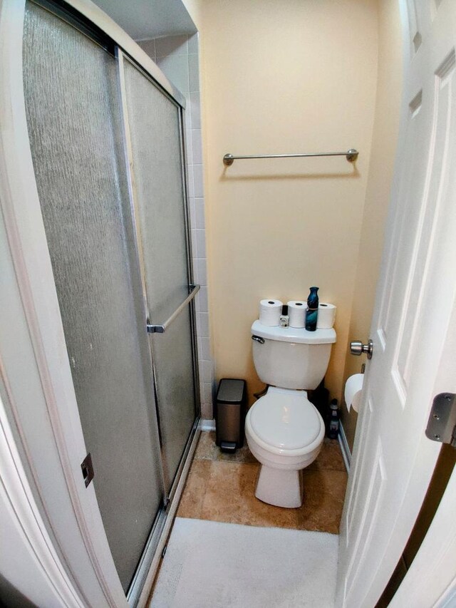 full bathroom featuring tile patterned flooring, a shower stall, toilet, and baseboards