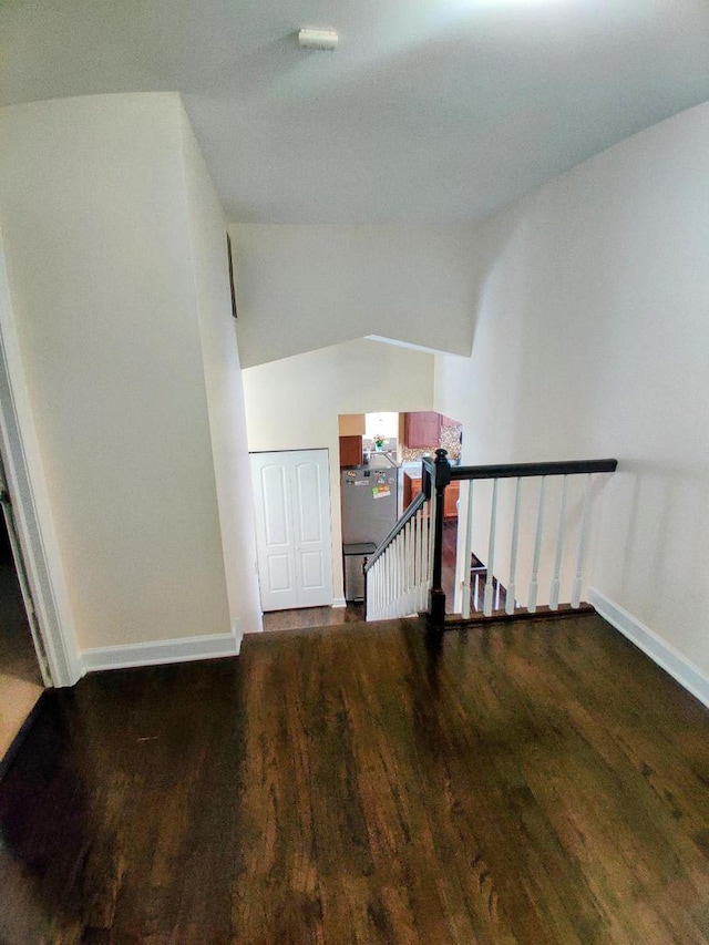 stairs featuring lofted ceiling, wood finished floors, and baseboards