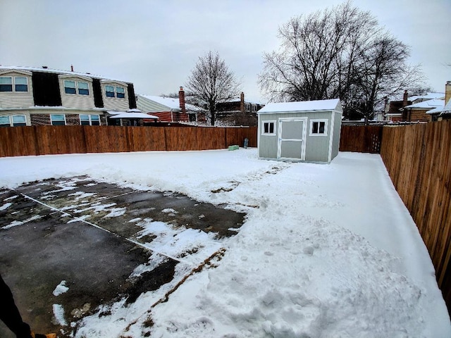 yard covered in snow with a storage unit, an outdoor structure, and a fenced backyard