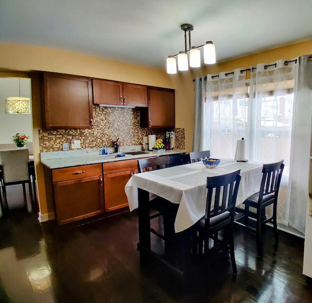 kitchen with a sink, backsplash, dark wood-style flooring, and light countertops