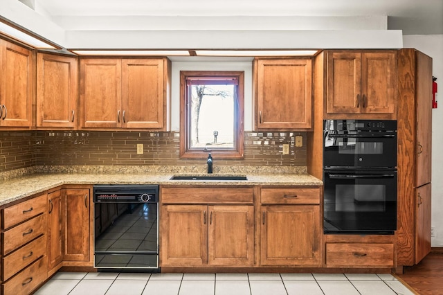 kitchen with a sink, decorative backsplash, black appliances, and brown cabinetry