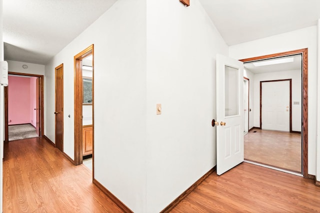 hallway with baseboards and light wood-style floors