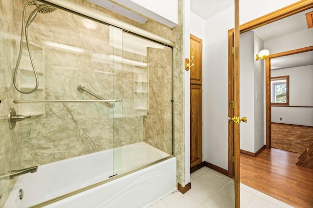 bathroom featuring tile patterned floors, baseboards, bath / shower combo with glass door, and a textured ceiling