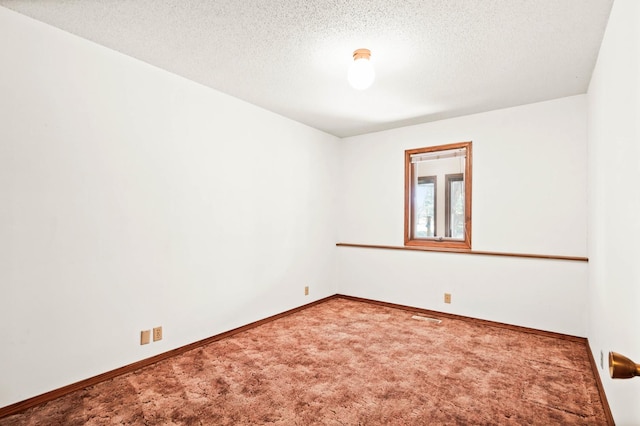 spare room with visible vents, a textured ceiling, baseboards, and carpet floors