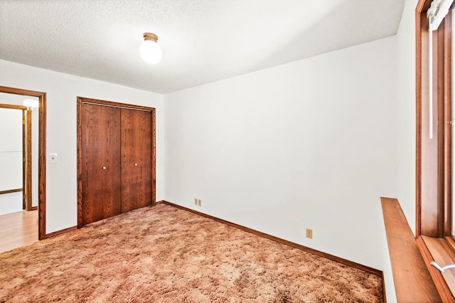 unfurnished bedroom with baseboards, a closet, carpet floors, and a textured ceiling