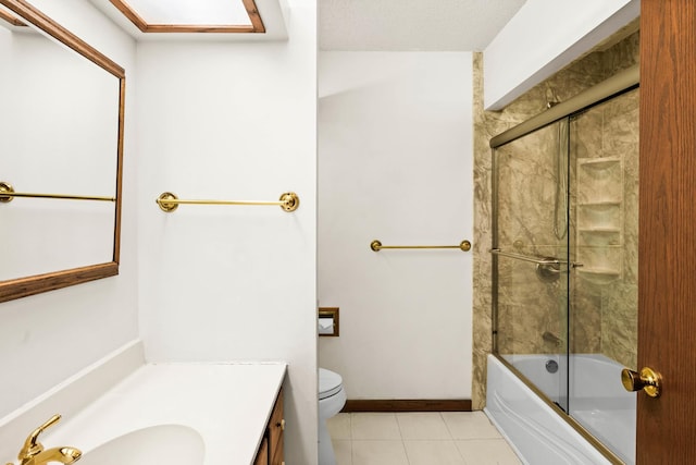 bathroom featuring toilet, shower / bath combination with glass door, tile patterned flooring, baseboards, and vanity