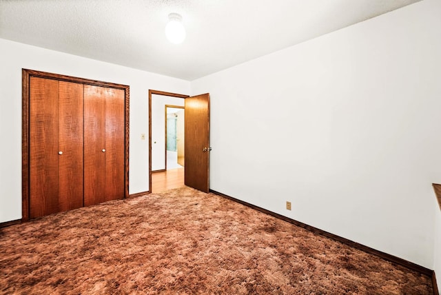 unfurnished bedroom with carpet flooring, baseboards, a closet, and a textured ceiling