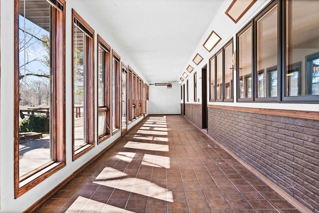 hall featuring dark tile patterned floors and brick wall