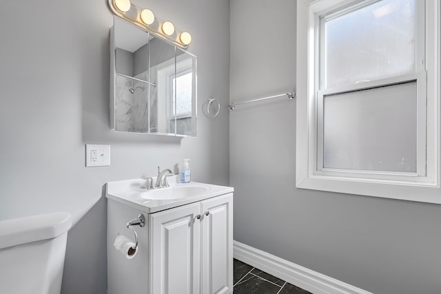 full bath featuring vanity, toilet, a shower, and baseboards