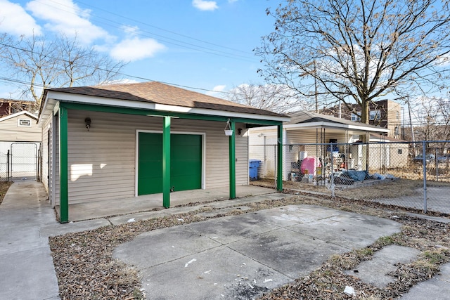 rear view of property featuring an outbuilding, a shingled roof, and fence