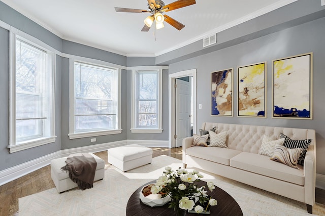 living area with crown molding, plenty of natural light, wood finished floors, and baseboards