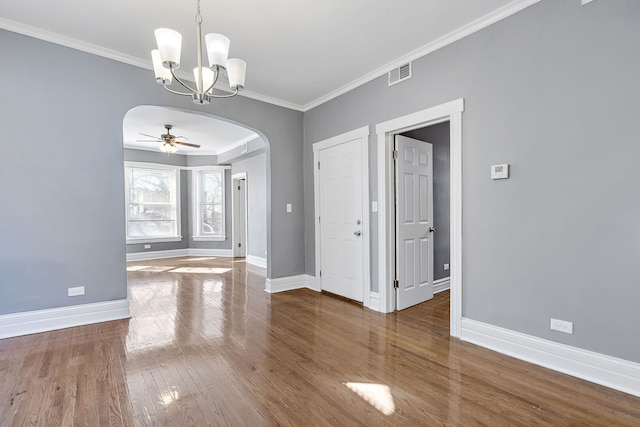 unfurnished room featuring visible vents, crown molding, baseboards, wood finished floors, and arched walkways