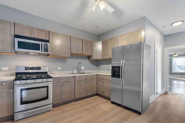 kitchen with appliances with stainless steel finishes, light countertops, a ceiling fan, and a sink